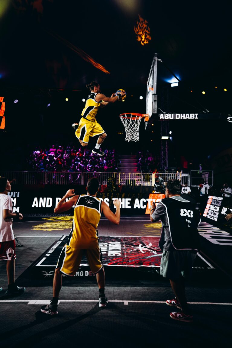 Basketball player elevating for a mid-air dunk, ball raised overhead, during a competitive game